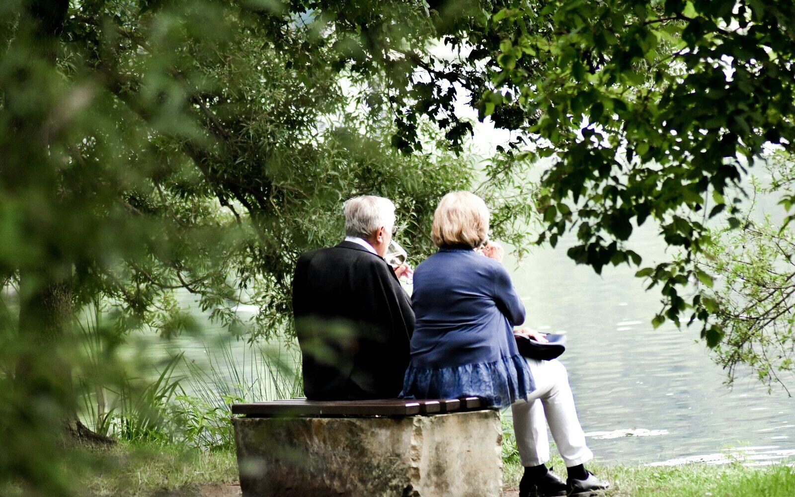Altersvorsorge: älteres Paar auf einer Bank am Wasser